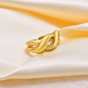 Macro view of a 18K gold plated knotted twist ring on a soft yellow silk background