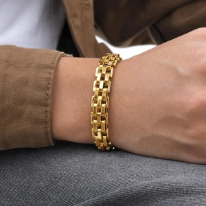Close-up of a polished golden stainless steel link bracelet on a wrist for men