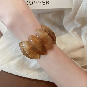 Detail view of amber resin chunky stretch bracelet on wrist with marbled pattern