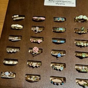 Set of assorted vintage gold-plated enamel and pearl rings on brown display stand