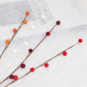 Detailed view of glossy artificial red and orange berries for seasonal DIY floral decor