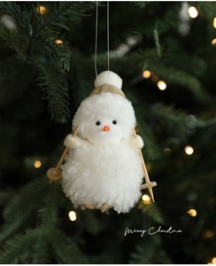 Detailed view of white plush snowman skier ornament hanging on a festive Christmas tree