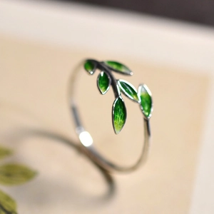 Detailed macro shot of a dainty silver ring featuring green enamel leaf craftsmanship