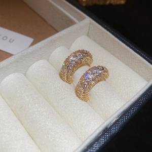 Macro shot of gold C-shaped hoop earrings with micro-paved zircons in a velvet gift box