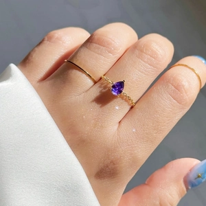 Détail de la bague en pierre violette taille poire avec anneau en chaîne dorée