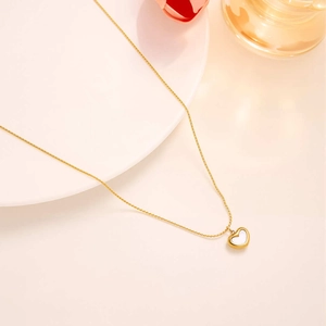 Detail of a gold heart pendant necklace featuring a white shell inlay on a soft background