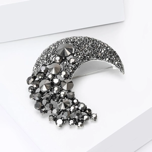 Detailed close-up of a moon-shaped brooch featuring elegant black rhinestones on a metal base