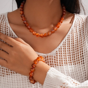 Close-up of ethnic acrylic beaded necklace and bracelet set in reddish brown marble finish