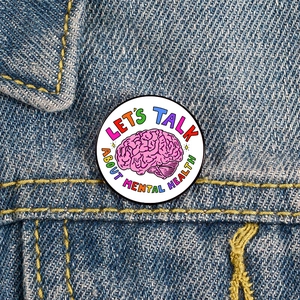 Detailed shot of Let's Talk About Mental Health enamel pin on a denim jacket