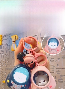 Close-up of luminous space cat keychains with glowing helmets and small bells