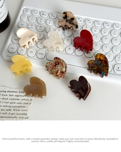 Close-up of colorful heart-shaped acetate hair claws on a desk with France Handmade text