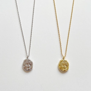 Detail of minimalist 925 silver irregular round pendants in gold and silver lava texture