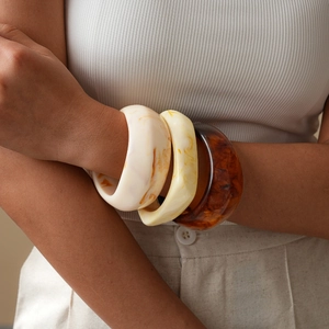 Close-up of bohemian resin bangles in amber, cream, and tortoiseshell on a wrist