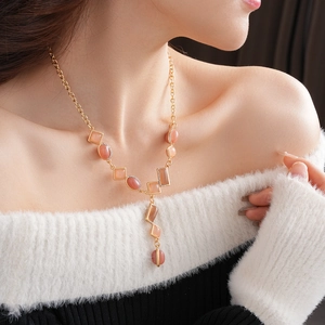 Close-up of vintage gold necklace with orange-red gems on model wearing off-shoulder top