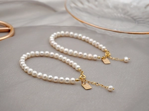 Detail of freshwater pearl bracelet with gold lobster clasp and Good Luck tag
