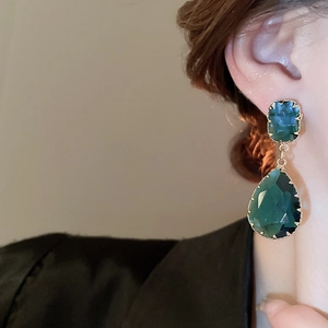 Detail of vintage drop earrings featuring blue square and green teardrop crystal stones