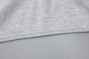 Close-up of grey ribbed knit crop top hemline showing high-quality stitching details