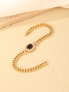 Macro detail of gold Cuban link bracelet with oval purple gemstone and zircon inlay