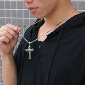 Close-up of double-layered silver cross pendant with thick rope chain on a male model