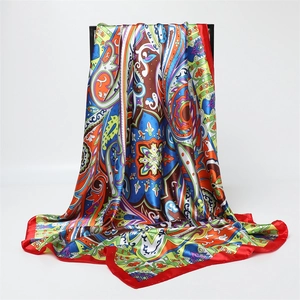 Detail of colorful paisley silk scarf with elegant red borders and satin finish