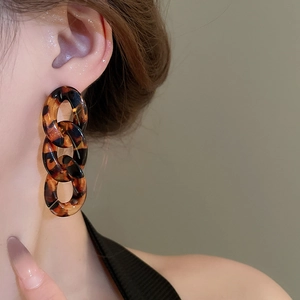 Macro detail of tortoiseshell acrylic chain drop earrings with amber leopard print texture