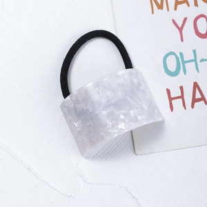 Detail view of a white marble acetate geometric hair tie with a black elastic band