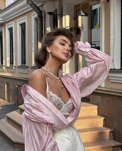 Detail showing pink satin blouse textures with lace lingerie and elegant accessories