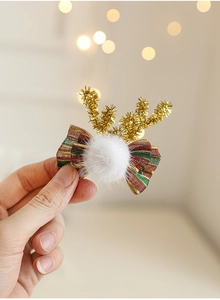 Détail d'une pince à cheveux renne de Noël avec pompons et nœud papillon à rayures