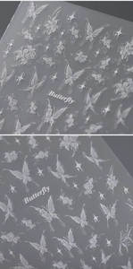 Close-up of 5D embossed white butterfly and floral nail art stickers with textured finish