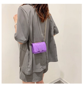 Detail of purple mini crossbody bag with heart relief on a grey suit jacket