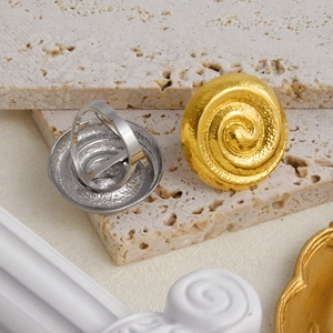 Detailed macro view of spiral texture earrings in gold and silver finishes on stone
