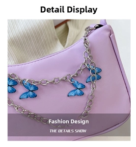 Detail shot of purple underarm bag featuring a silver butterfly charm metal chain