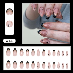 Detail of almond-shaped French press-on nails with black tips and gold glitter stars