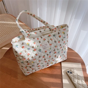 Close-up of quilted floral tote bag with bear print on a rustic wooden table setup