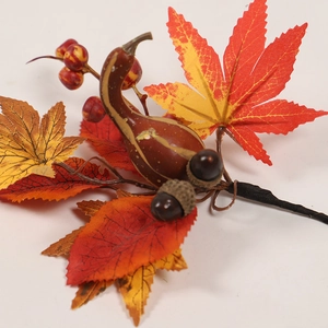 Detail of autumn branch with orange maple leaves, red berries, and mini gourds