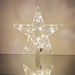 Close-up of a clear star tree topper with warm white LED lights and ornate swirl patterns