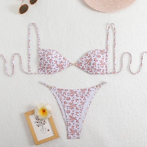 Detailed flat lay of a floral bikini with gold rings and elegant pearl embellishments