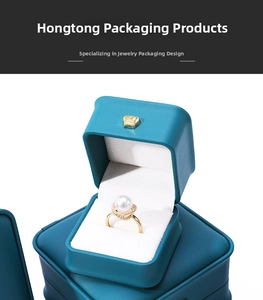 Detail of luxury teal crown jewelry box with white velvet lining and pearl ring inside