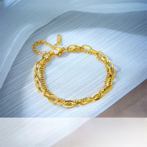 Detail of a gold double-layer chain bracelet with heart charm and lobster clasp
