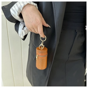 Detail of a bright orange sequined mini cylinder pouch with golden metal keychain clasp