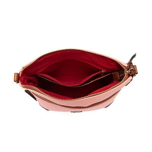 Macro view of multi-compartment pink pebbled leather crossbody bag with red fabric lining