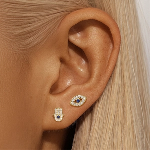 Macro shot of 18K gold plated S925 silver devil eye and hamsa hand stud earrings