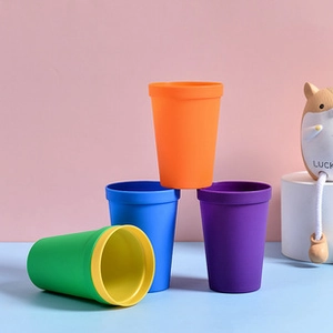 Close-up of colorful stacking cups in vibrant orange and blue on a soft pink background