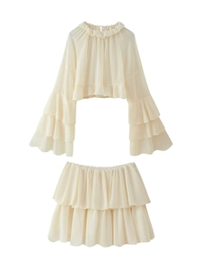 Dettaglio del completo due pezzi in chiffon crema con top a volant e gonna a balze