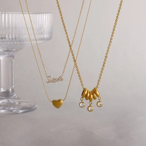 Détail de colliers superposés plaqués or 18 carats avec pendentifs Love et coeur