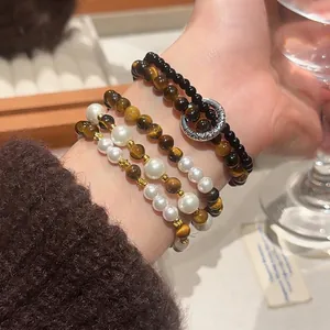 Retro tiger eye and pearl beaded bracelet layered with gold spacers on woman's wrist
