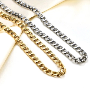 Primo piano di catene cubane in acciaio inossidabile oro e argento su tessuto beige