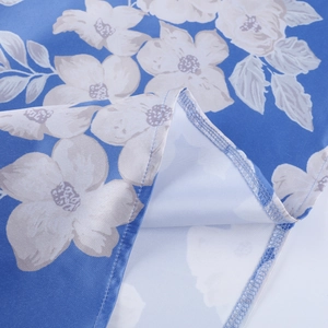 Close-up of the hem stitching and white floral print on the blue summer dress fabric