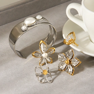 Mixed metal jewelry set with pearl bracelets and zircon rings on a marble background