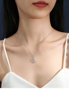 Detail of water drop moissanite pendant on a silver necklace worn by a model